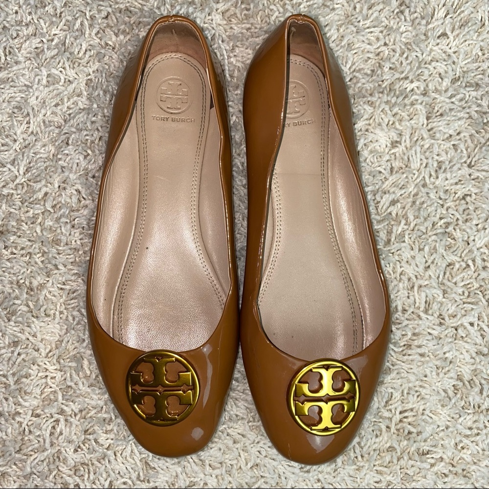 Tory Burch tan patent leather slip on flats with large gold logo